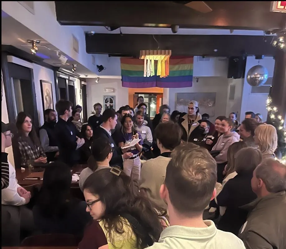 A packed upstairs room at Dupont Italian Kitchen, with a rainbow flag over the doorway, during a Dupont Neighbors happy hour